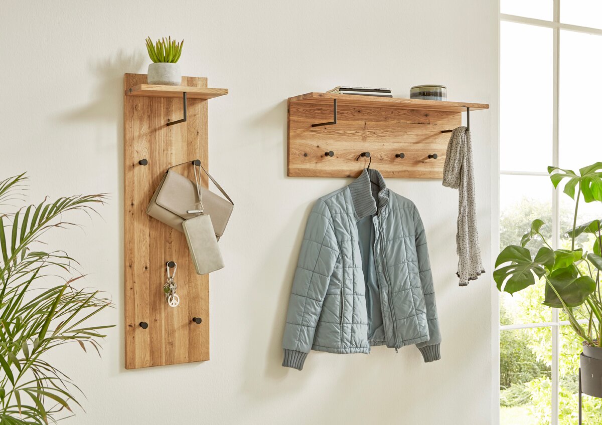 Zwei Wandgarderoben aus massivem Holz mit schwarzem Metallhaken und Ablage, seitliche Frontansicht im hellen Flur; links schmales Garderobenpaneel mit Tasche und Schlüssel, rechts breites Garderobenboard mit Jacke und Schal