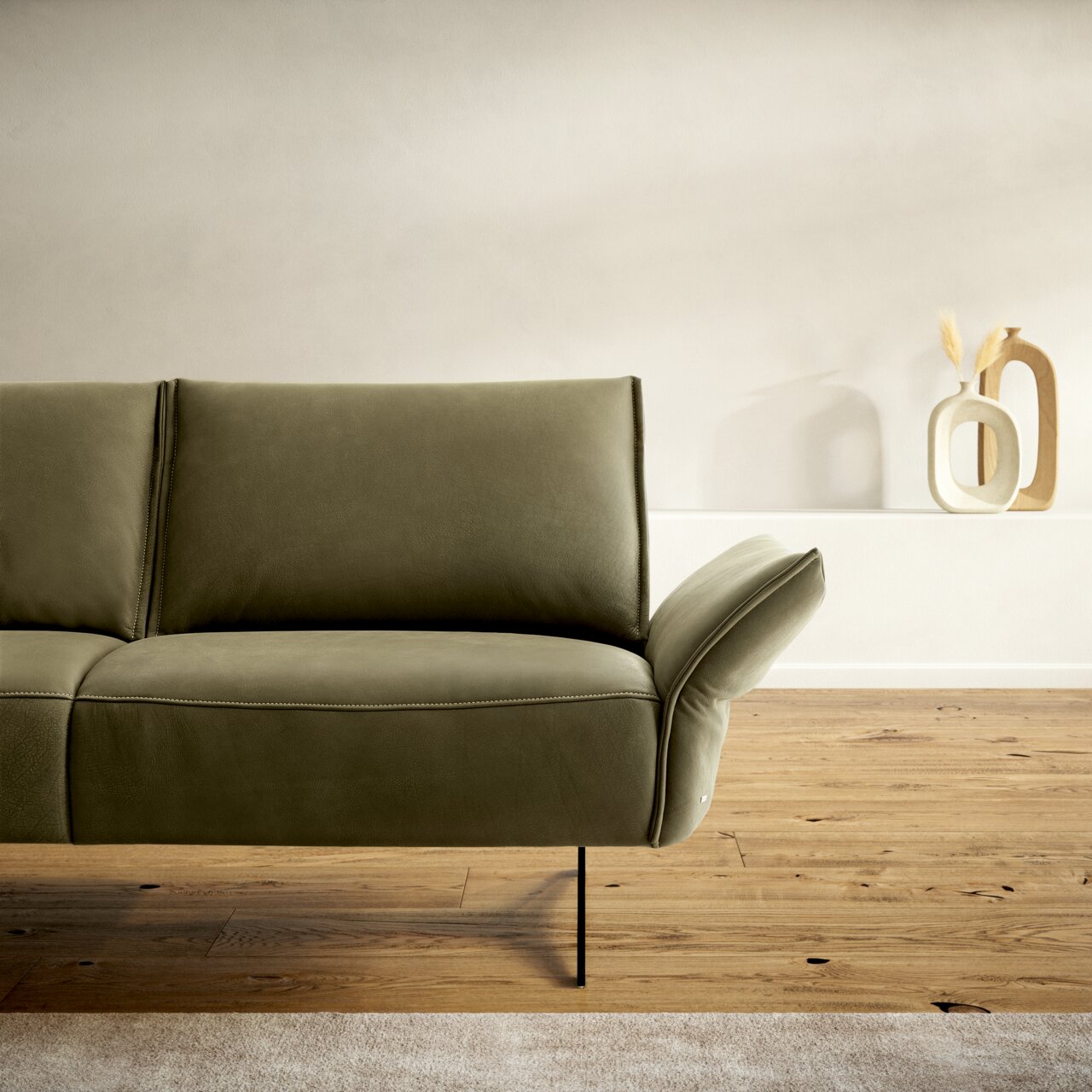 Grüne Polsterrundecke in modernem Design, seitliche Perspektive, auf Holzfußboden mit dekorativen Vasen im Hintergrund.