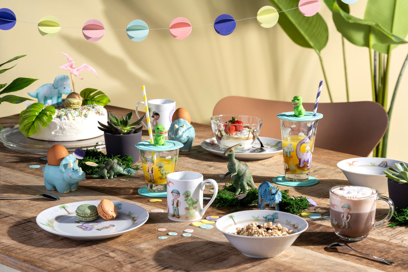 Kindergeschirrset mit Dinosaurier-Motiven auf einem gedeckten Tisch, seitliche Perspektive