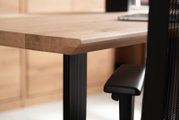 Nahaufnahme eines Schreibtisches mit Holzplatte und schwarzem Metallgestell, seitliche Perspektive