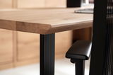Nahaufnahme eines Schreibtisches mit Holzplatte und schwarzem Metallgestell, seitliche Perspektive