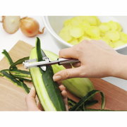 Nahaufnahme eines Pendelschälers PROFI PLUS, der eine Gurke schält. Der Schäler wird von einer Hand gehalten und zeigt die Funktionalität des Produkts.