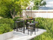 Bar-Set im Garten mit Tisch und Hockern, umgeben von grünen Pflanzen, aus der Perspektive von vorne.