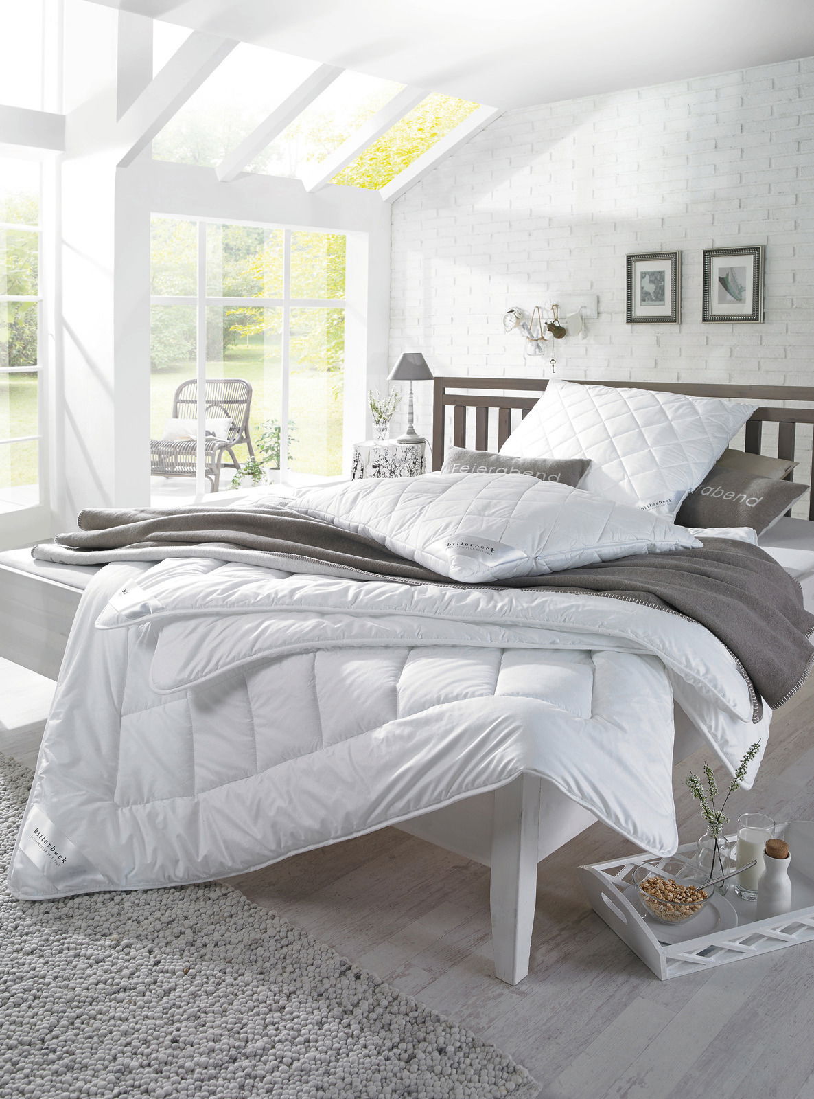 billerbeck Kopfkissen WASH Ein gemütliches Schlafzimmer mit einem weißen, gesteppten Kopfkissen und einer passenden Bettdecke auf einem modernen Bett. Die Perspektive zeigt das Bett von der Seite, mit einem Fenster im Hintergrund, das natürliches Licht hereinlässt.