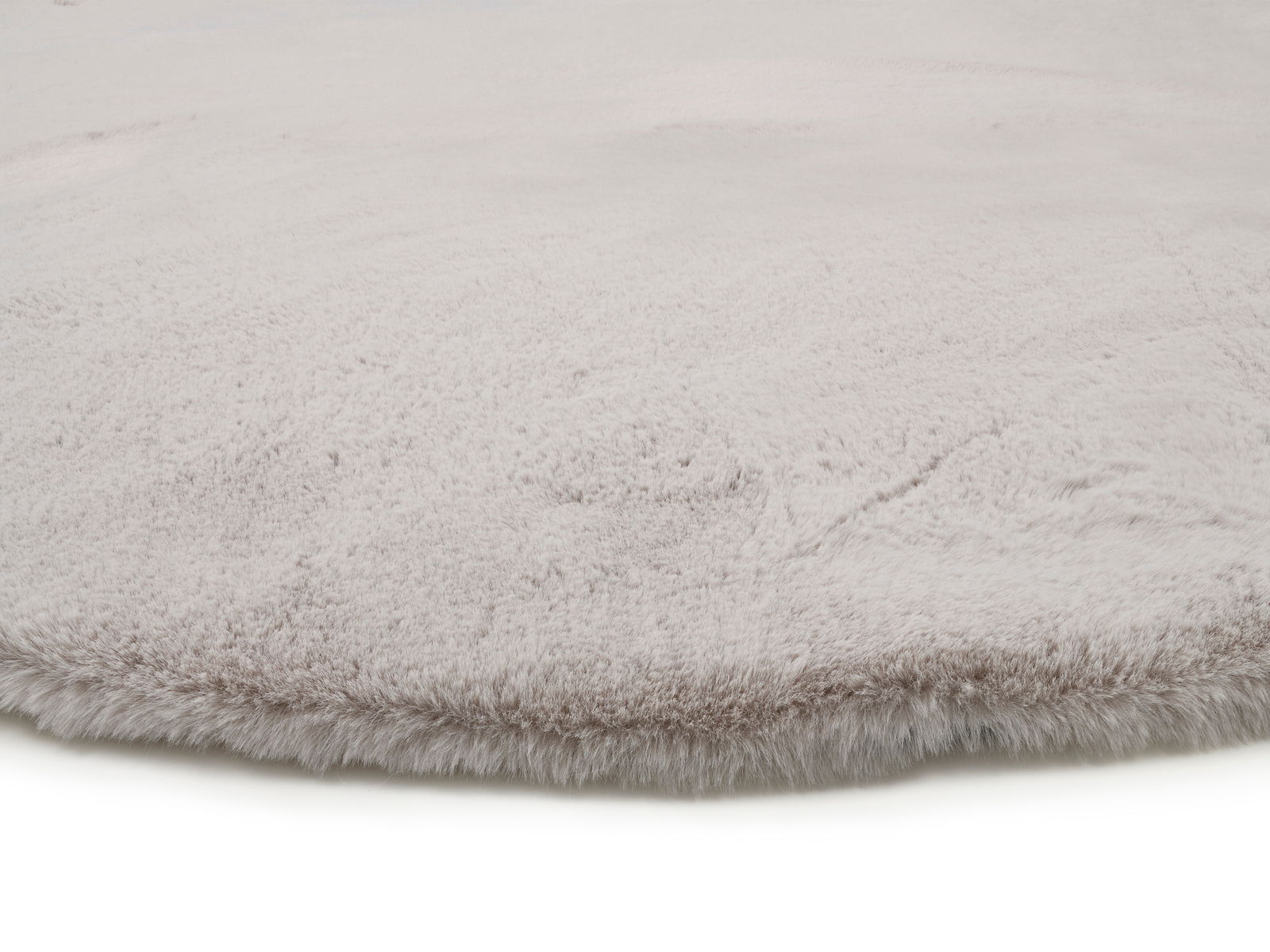 Nahaufnahme eines weichen, hellgrauen Fellteppichs mit flauschiger Textur.
