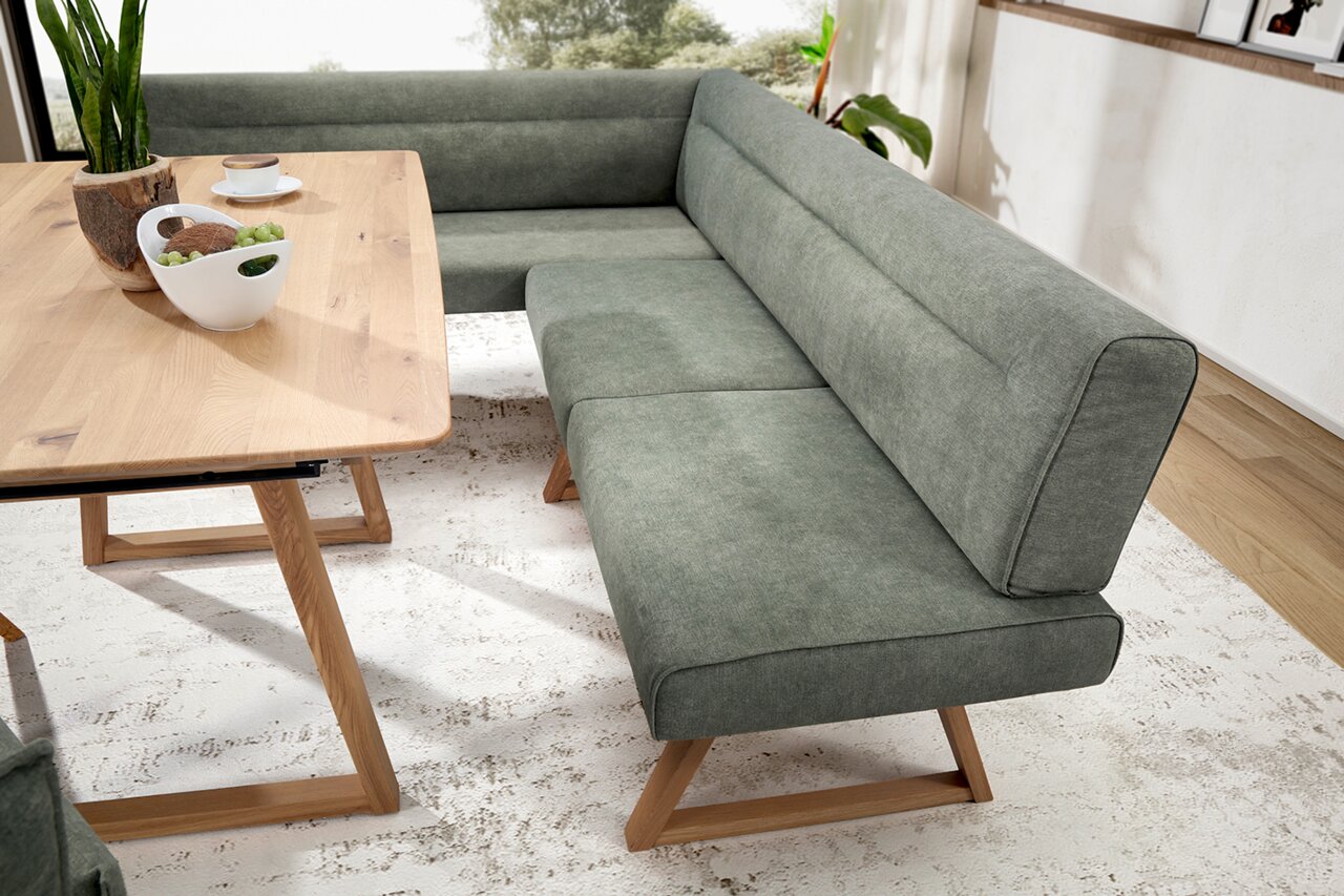 Eckbank in modernem Design mit grauem Stoffbezug und Holzbeinen, seitliche Perspektive.