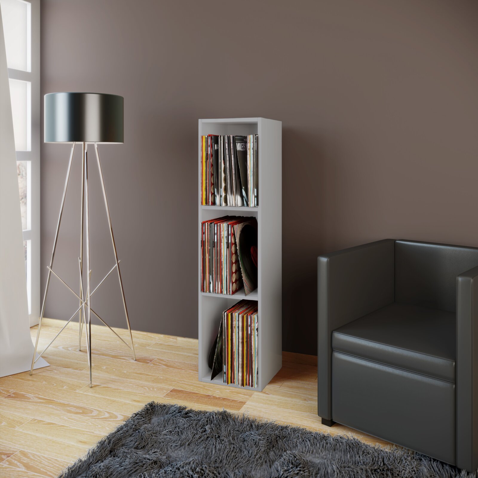 Weißes, schmales Regal für Schallplatten/Vinyl mit drei Fächern, gefüllt mit LPs, im Wohnzimmer neben Stehlampe und Sofa, Frontansicht in leichter Schrägperspektive