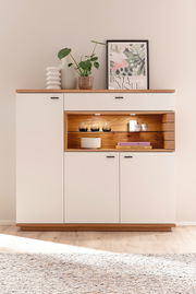 Modernes Highboard in Weiß mit Holzdetails, dekoriert mit Pflanzen und Kunst, aus frontaler Perspektive.