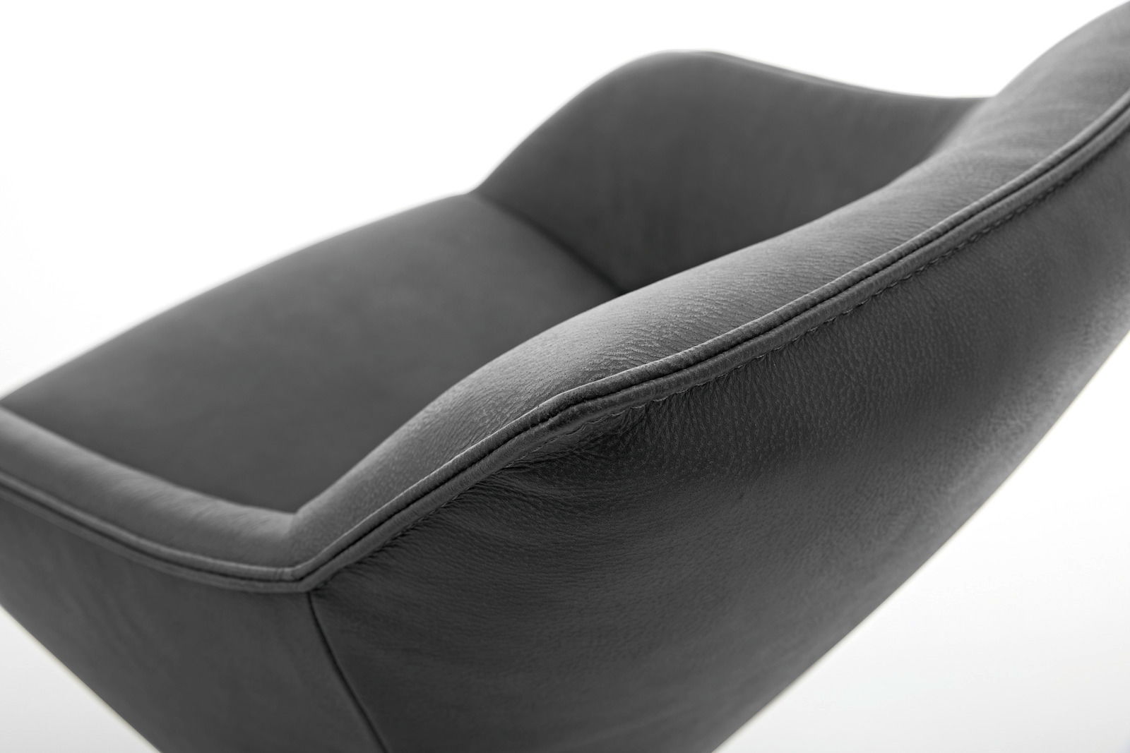 Nahaufnahme eines modernen, dunkelgrauen Sessels aus Leder mit geschwungenen Linien, seitliche Perspektive.