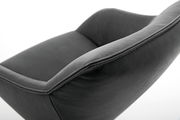 Nahaufnahme eines modernen, dunkelgrauen Sessels aus Leder mit geschwungenen Linien, seitliche Perspektive.