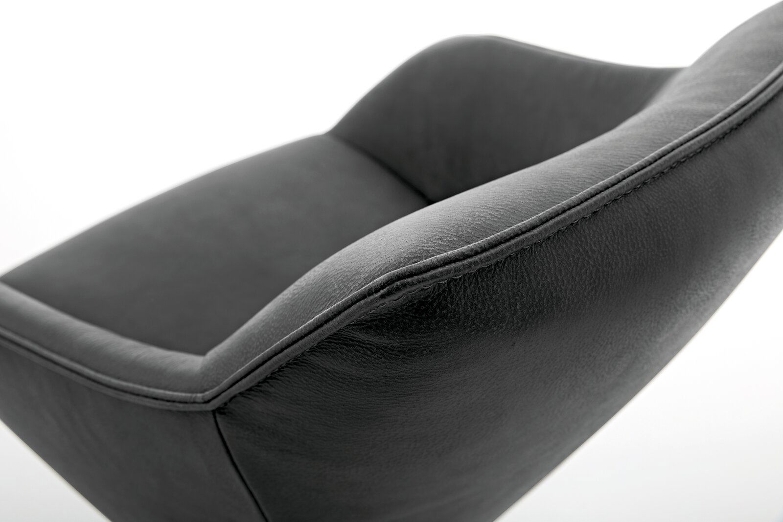 Nahaufnahme eines modernen, dunkelgrauen Sessels aus Leder mit geschwungenen Linien, seitliche Perspektive.