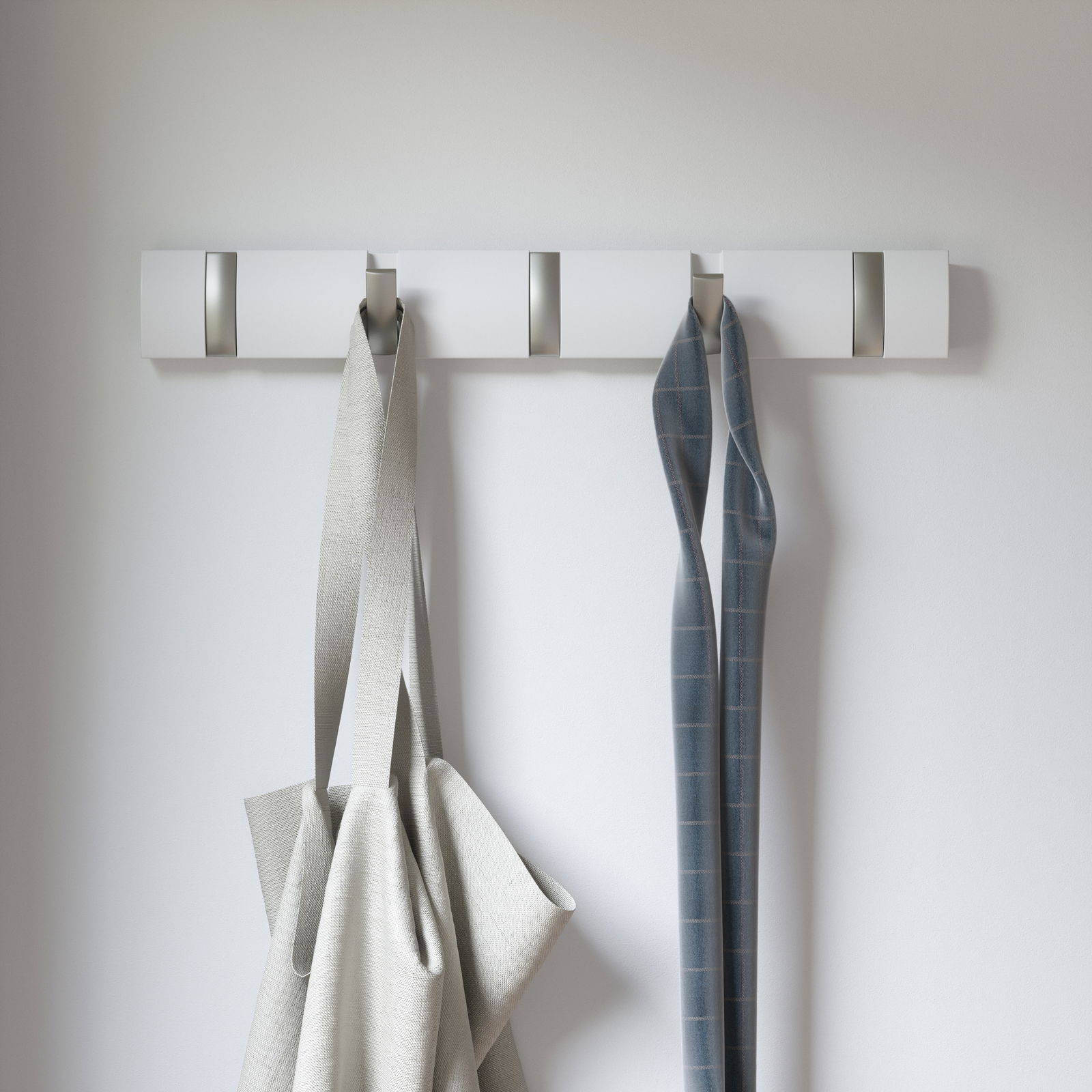 Moderne Wandgarderobe mit mehreren Haken, frontal fotografiert, mit aufgehängten Stoffen.