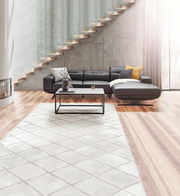 Moderne schwarze XORA Longchairkombination ROM in einem stilvollen Wohnzimmer mit Holzfußboden und Treppe im Hintergrund, Perspektive von vorne.