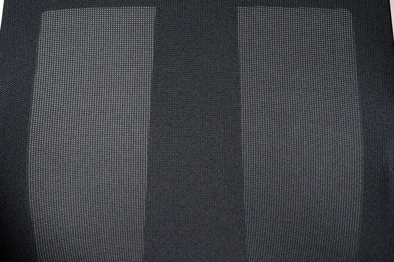 Nahaufnahme der Rückenlehne eines Drehstuhls mit grauem Netzstoff, von vorne betrachtet.