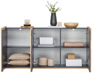 Offenes Sideboard mit zwei Türen, gefüllt mit Kissen, Boxen und Dekorationen, aus der Frontperspektive.