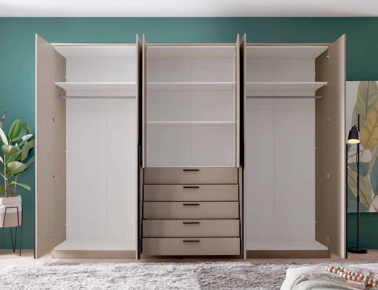 Offener dreitüriger Kleiderschrank in Beige mit weißem Innenraum, zwei Kleiderstangen, mehreren Einlegeböden und fünf Schubladen in der Mitte, frontal aus Augenhöhe fotografiert