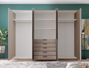 Open drievleugelige kledingkast in beige met een witte binnenkant, twee kledingstangen, meerdere legplanken en vijf lades in het midden, van voren gefotografeerd op ooghoogte