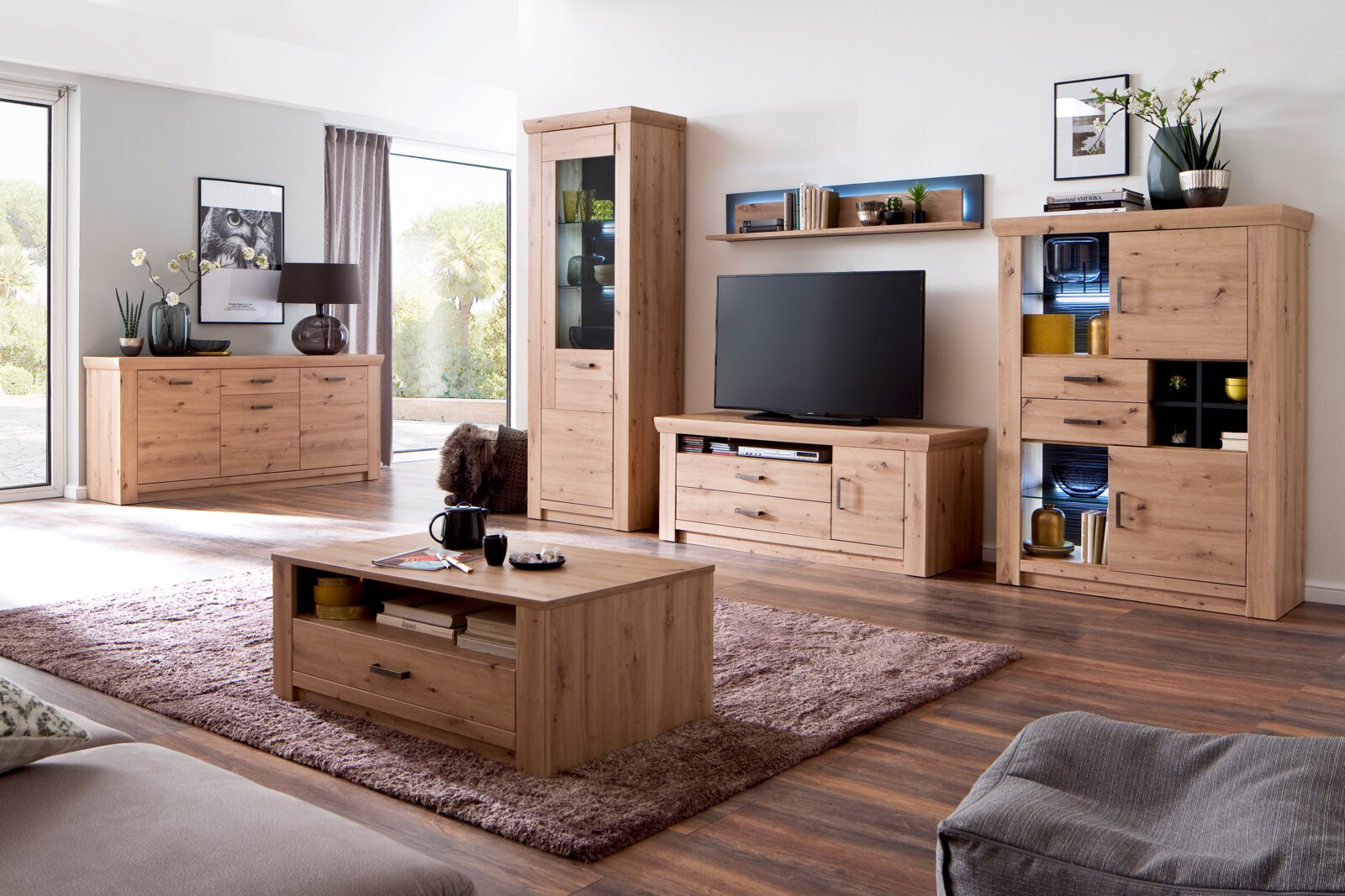 Moderner Wohnraum mit einem Couchtisch aus Holz in der Mitte, umgeben von passenden Möbeln in heller Holzoptik. Perspektive von vorne auf den Tisch.