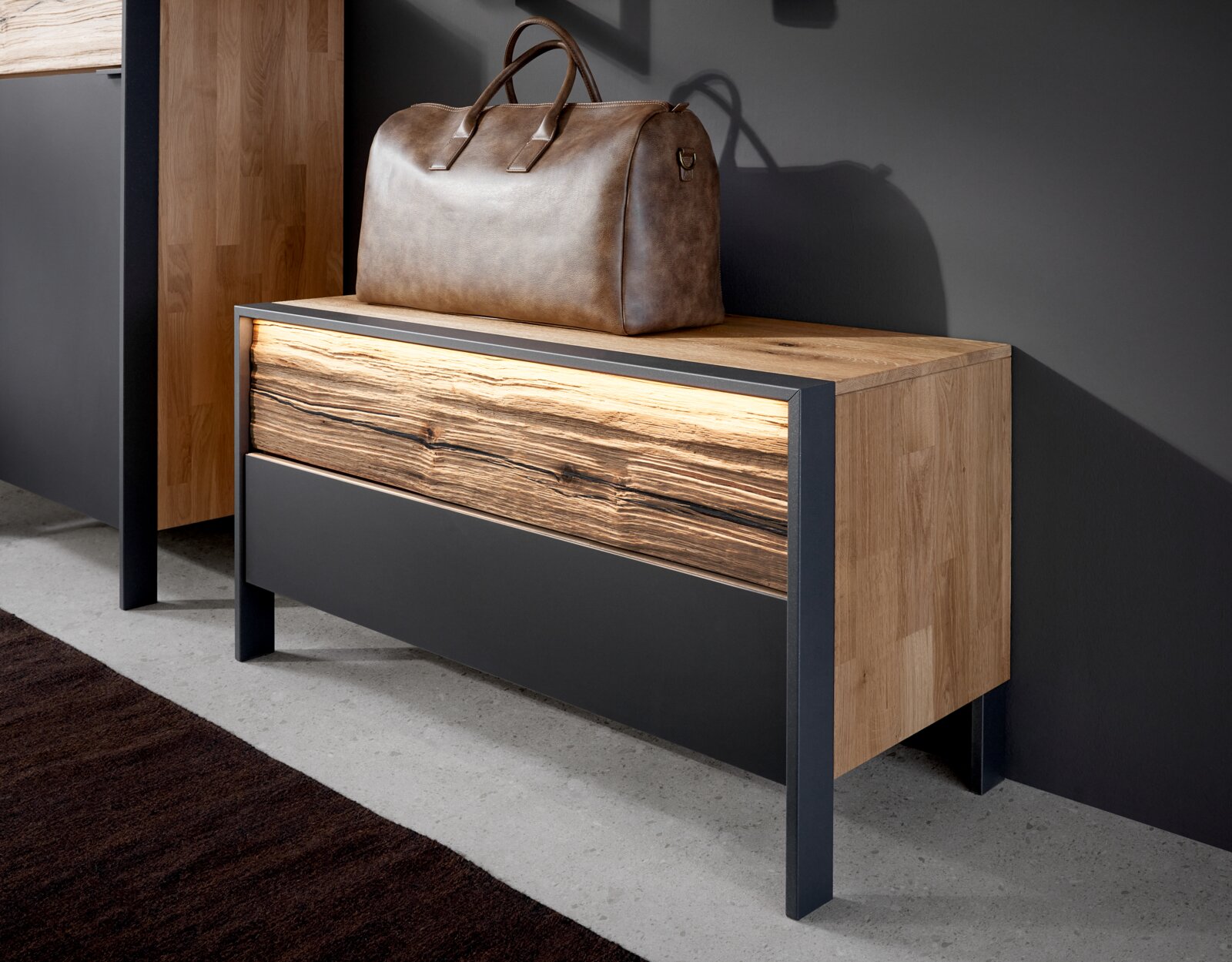 Garderobenbank aus Holz mit Metallrahmen, seitliche Perspektive, darauf eine braune Ledertasche