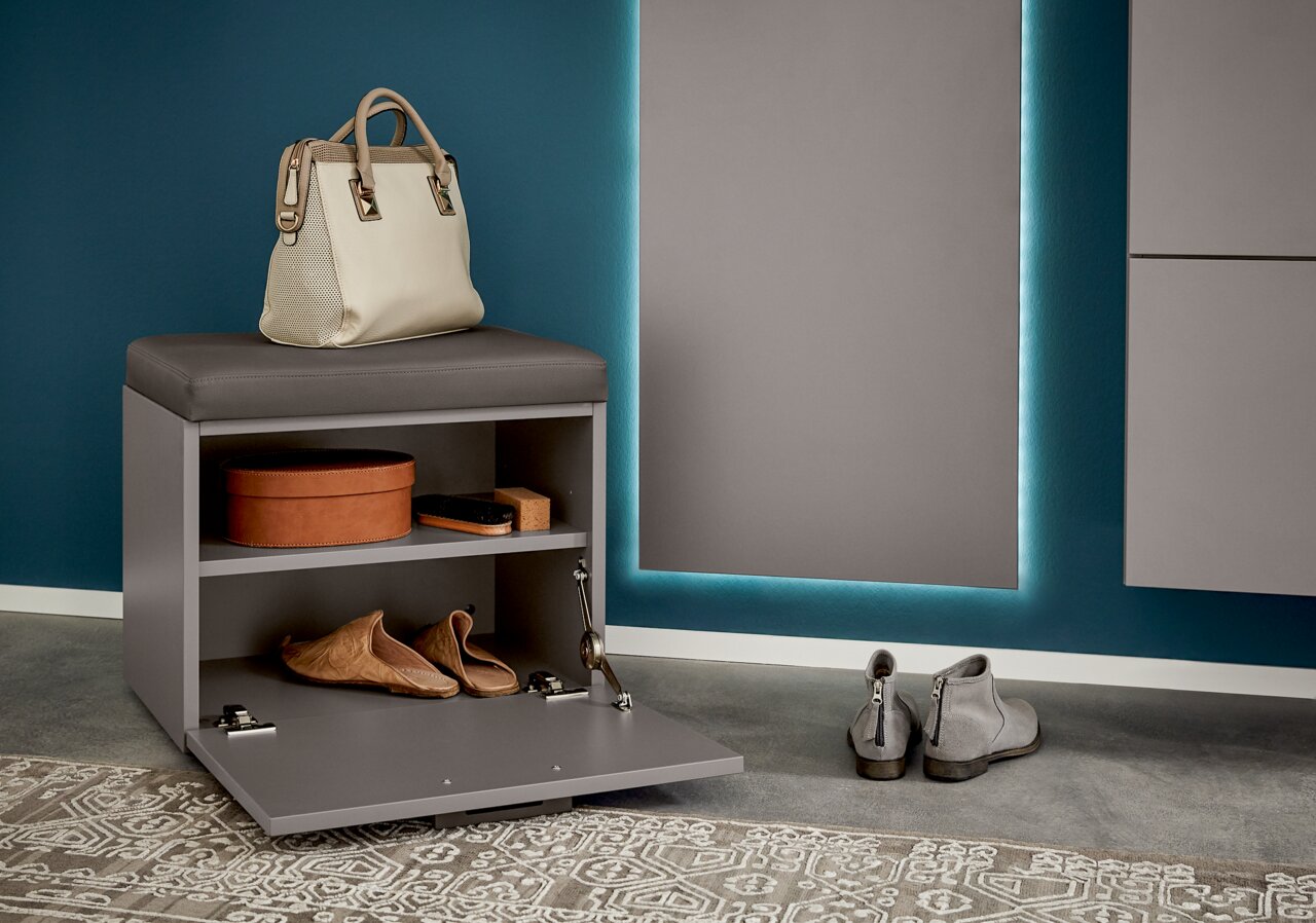 Garderoben-Set mit grauem Sitzhocker, geöffnetem Fach mit Schuhen und Accessoires, seitliche Perspektive