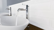 Moderne Waschtischarmatur in seitlicher Perspektive mit fließendem Wasser in einem stilvollen Badezimmer.