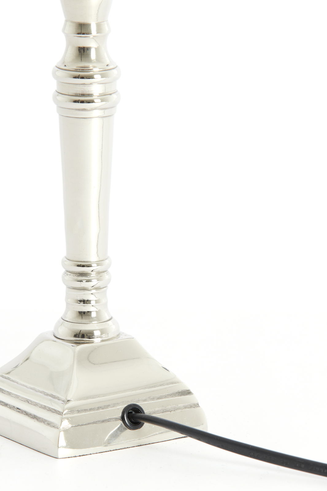 Nahaufnahme eines eleganten, vernickelten Lampenfußes mit quadratischer Basis und Kabelanschluss, seitliche Perspektive.