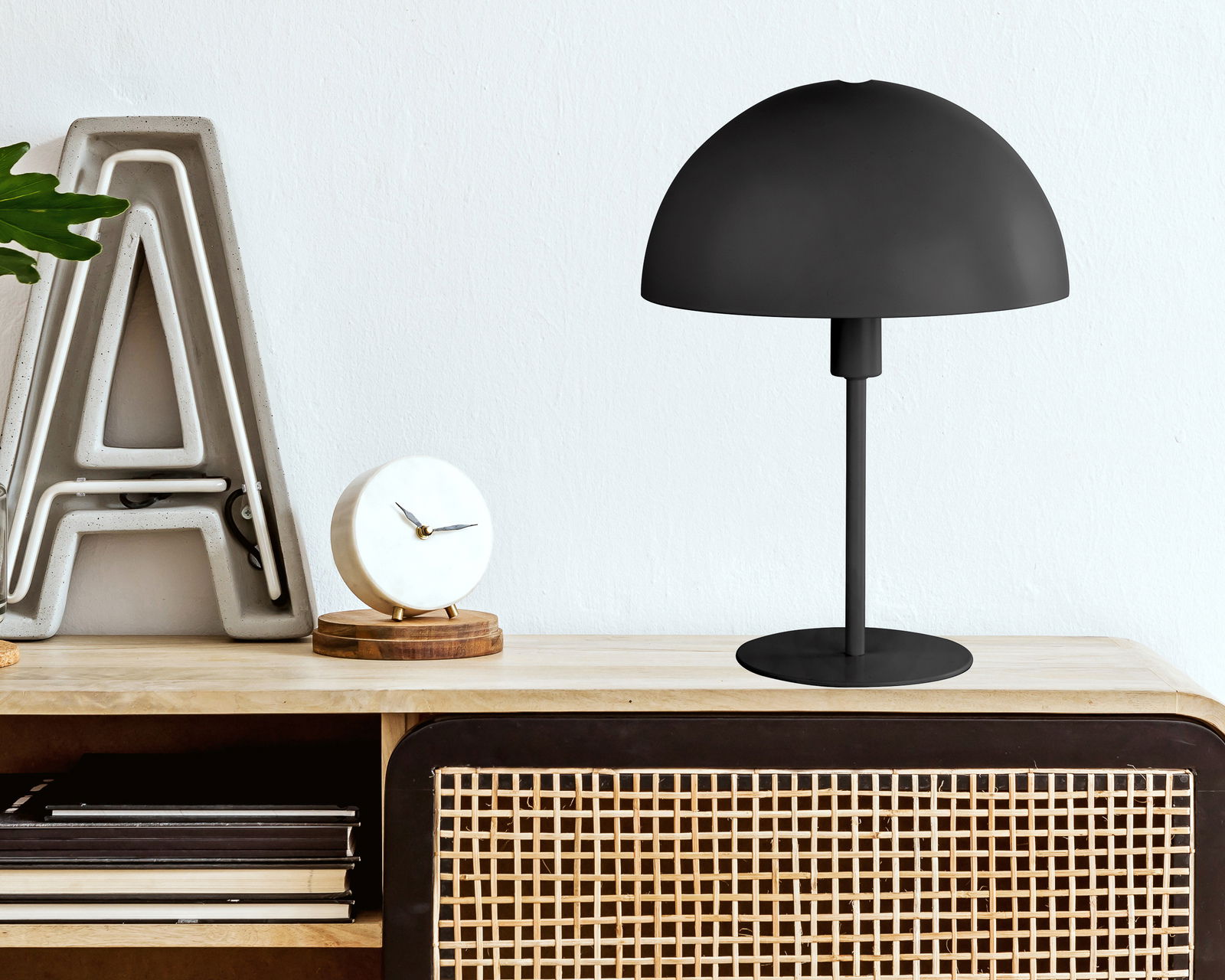 NOWA Tischleuchte MEIKE MEIKE Schwarze Tischleuchte MEIKE mit halbrundem Schirm auf einem Holzschrank, seitliche Perspektive