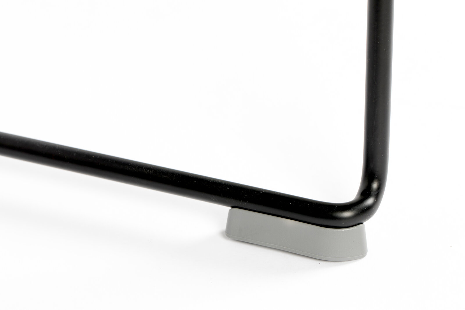 Nahaufnahme eines schwarzen Stuhlbeins mit grauem Bodenschutz, seitliche Perspektive