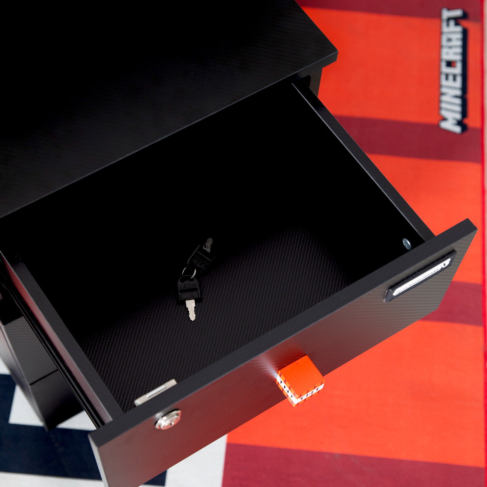 Zurbrüggen Rollcontainer MINECRAFT Offene schwarze Schublade mit Carbon-Optik und Schloss, innen mit Schlüssel auf rutschfester Einlage, fotografiert aus schräger Draufsicht