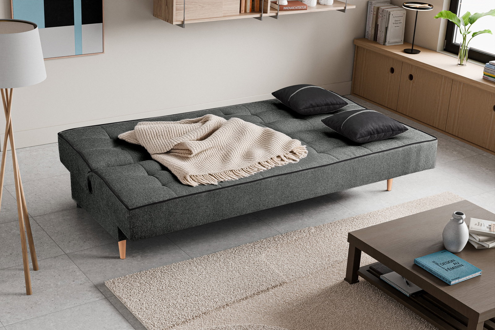 Schlafsofa 3 Sitzer in einem modernen Wohnzimmer, von oben betrachtet, mit grauem Stoffbezug, zwei schwarzen Kissen und einer beigen Decke.