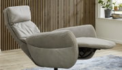 Grijze relaxfauteuil in zijaanzicht met opgeklapte voetsteun voor een houten wand.