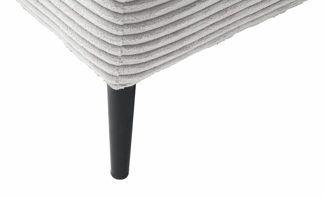 Nahaufnahme eines Longchairs mit geripptem Stoffbezug und schwarzem Bein, Perspektive von unten.