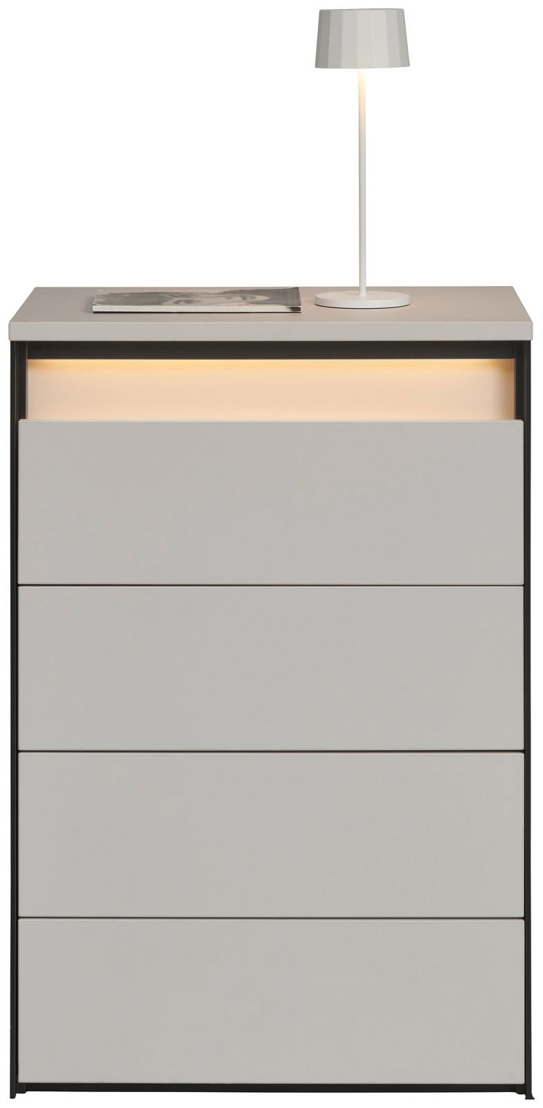 Hochkommode mit vier Schubladen, grauer Oberfläche und integrierter Beleuchtung, frontal betrachtet. Auf der Oberseite steht eine weiße Lampe und ein Buch.
