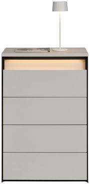 Hochkommode mit vier Schubladen, grauer Oberfläche und integrierter Beleuchtung, frontal betrachtet. Auf der Oberseite steht eine weiße Lampe und ein Buch.