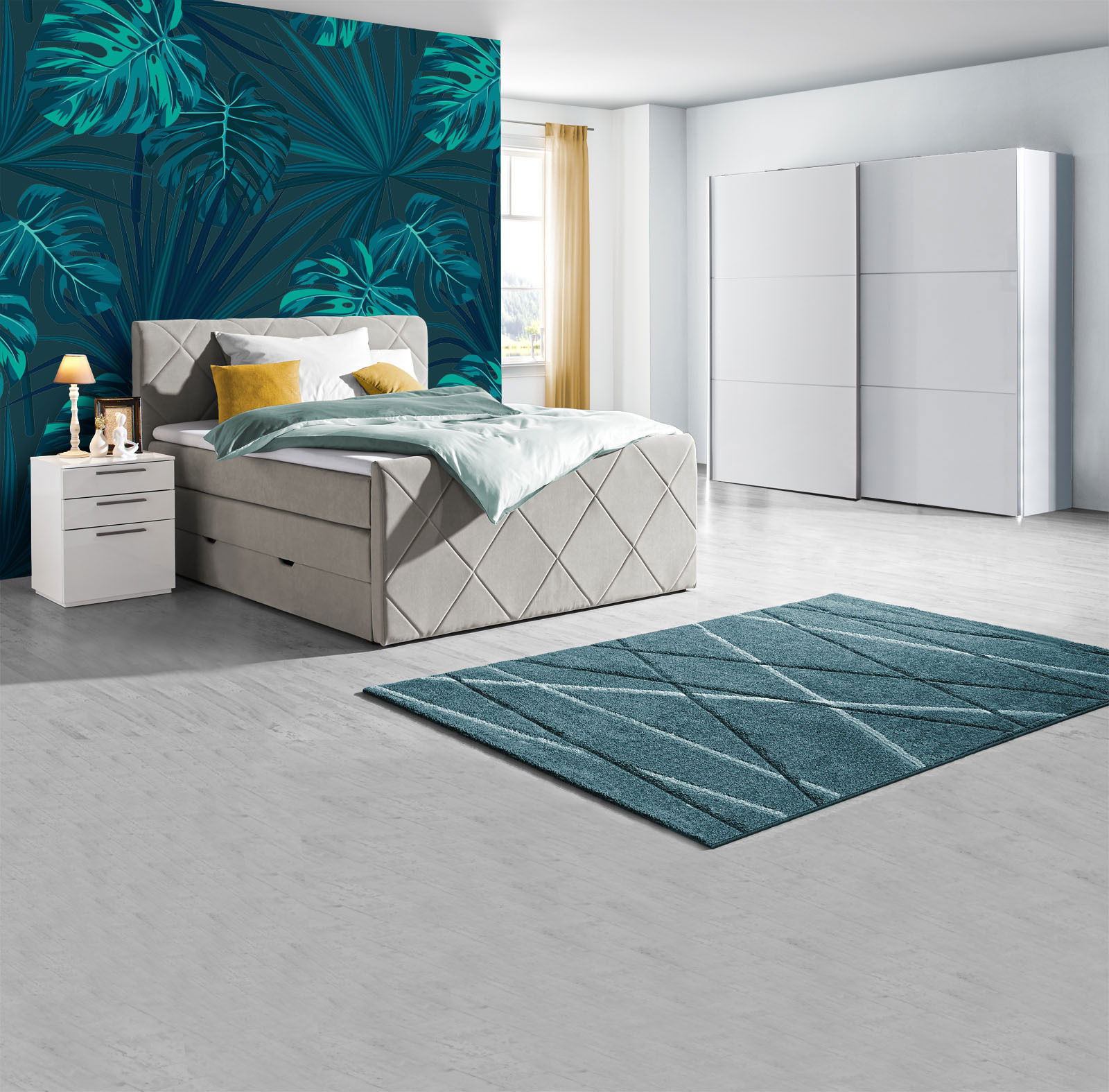 Modernes Schlafzimmer mit Boxspringbett in hellem Stoff, zwei weißen Nachttischen, einem großen weißen Schwebetürenschrank und einem türkisfarbenen Teppich, seitliche Perspektive.
