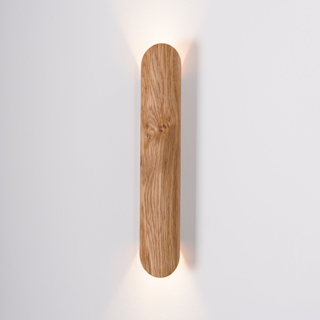 LED-Wandleuchte aus Holz mit vertikaler Ausrichtung, warmes Licht strahlt nach oben und unten, frontale Ansicht.