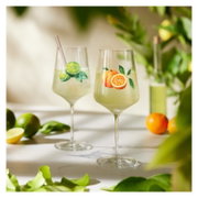 Zwei elegante Cocktailgläser mit frischem Zitrusdrink und Fruchtmotiven (Orange und Limette) auf hellem Tisch, Perspektive: frontale Nahaufnahme auf Augenhöhe mit leichtem Hintergrund-Bokeh.