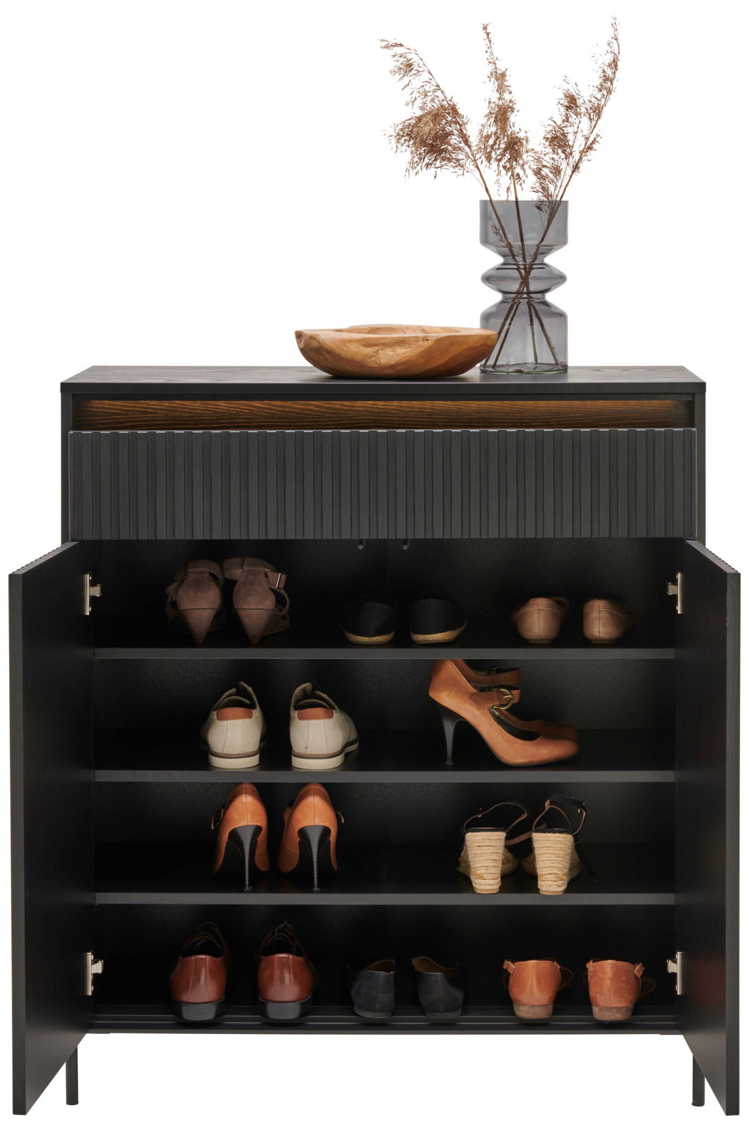 Moderner Schuhschrank mit geöffneter Tür, gefüllt mit verschiedenen Schuhen, dekoriert mit einer Holzschale und einer Vase mit getrockneten Gräsern auf der Oberseite, Frontalansicht.