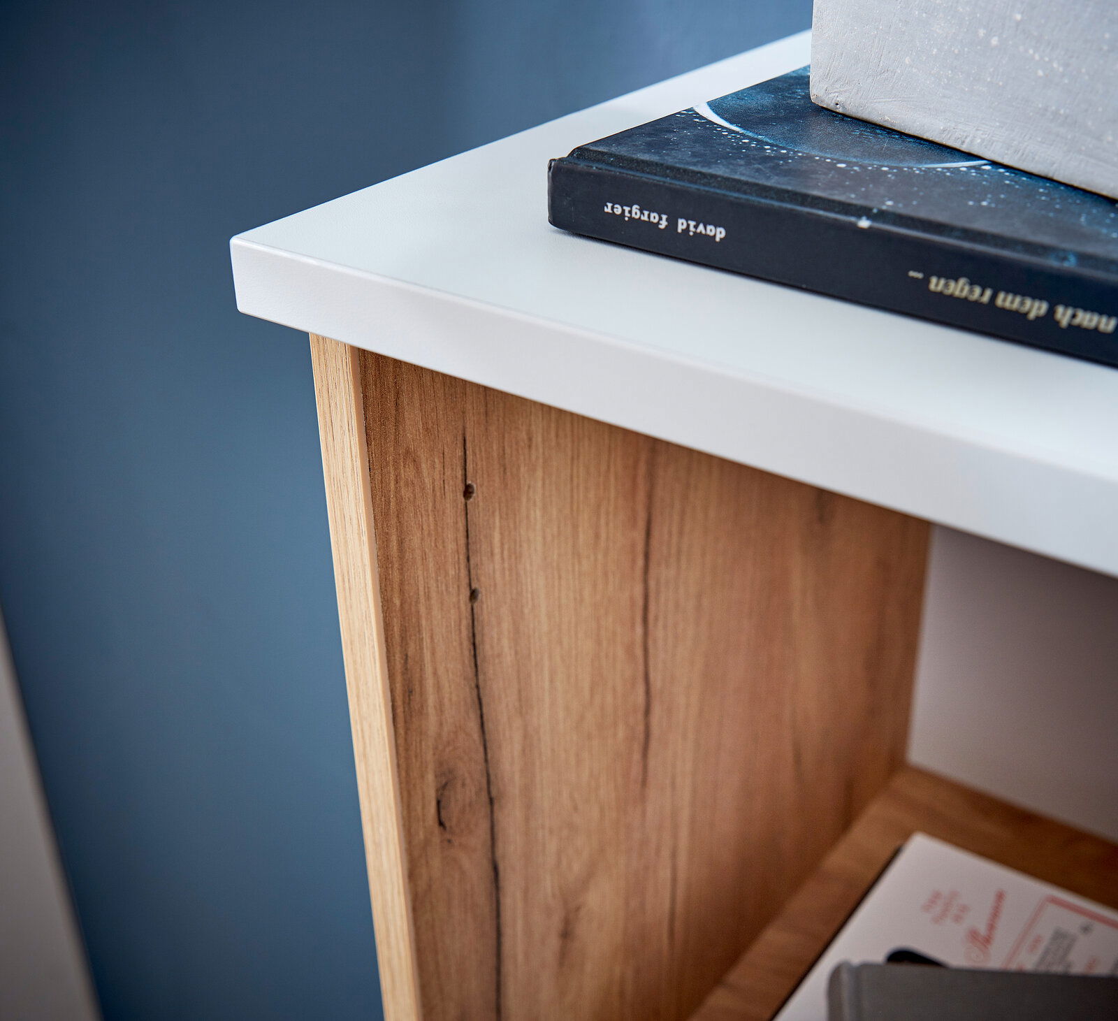Nahaufnahme eines Aktenschranks mit weißer Oberseite und Holzmaserung, von oben betrachtet.