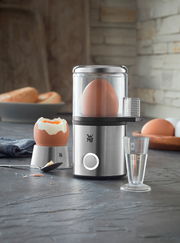 Eierkocher MyEgg Küchenminis in Edelstahloptik, frontal abgebildet mit einem Ei im Kocher und einem gekochten Ei daneben.