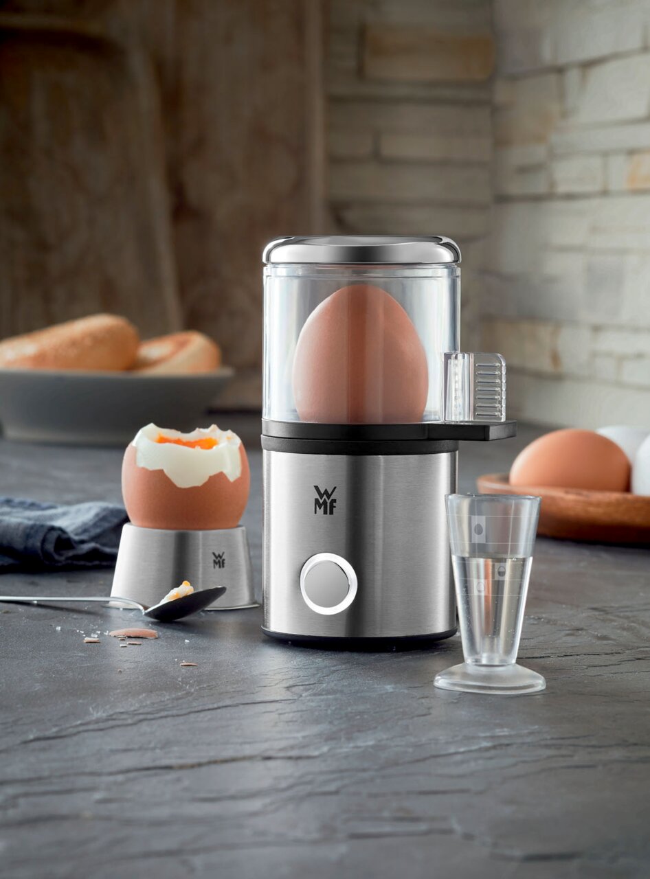 WMF Küchenminis 1-Ei-Kocher My Egg Eierkocher MyEgg Küchenminis in Edelstahloptik, frontal abgebildet mit einem Ei im Kocher und einem gekochten Ei daneben.