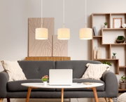 Drei moderne Hängeleuchten in einem gemütlichen Wohnzimmer, frontal betrachtet.