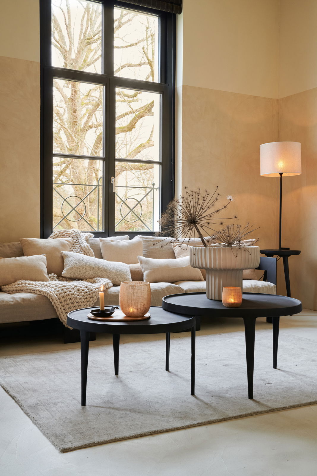 Stehlampe mit schlichtem, hellem Lampenschirm in einem gemütlichen Wohnzimmer, seitliche Perspektive