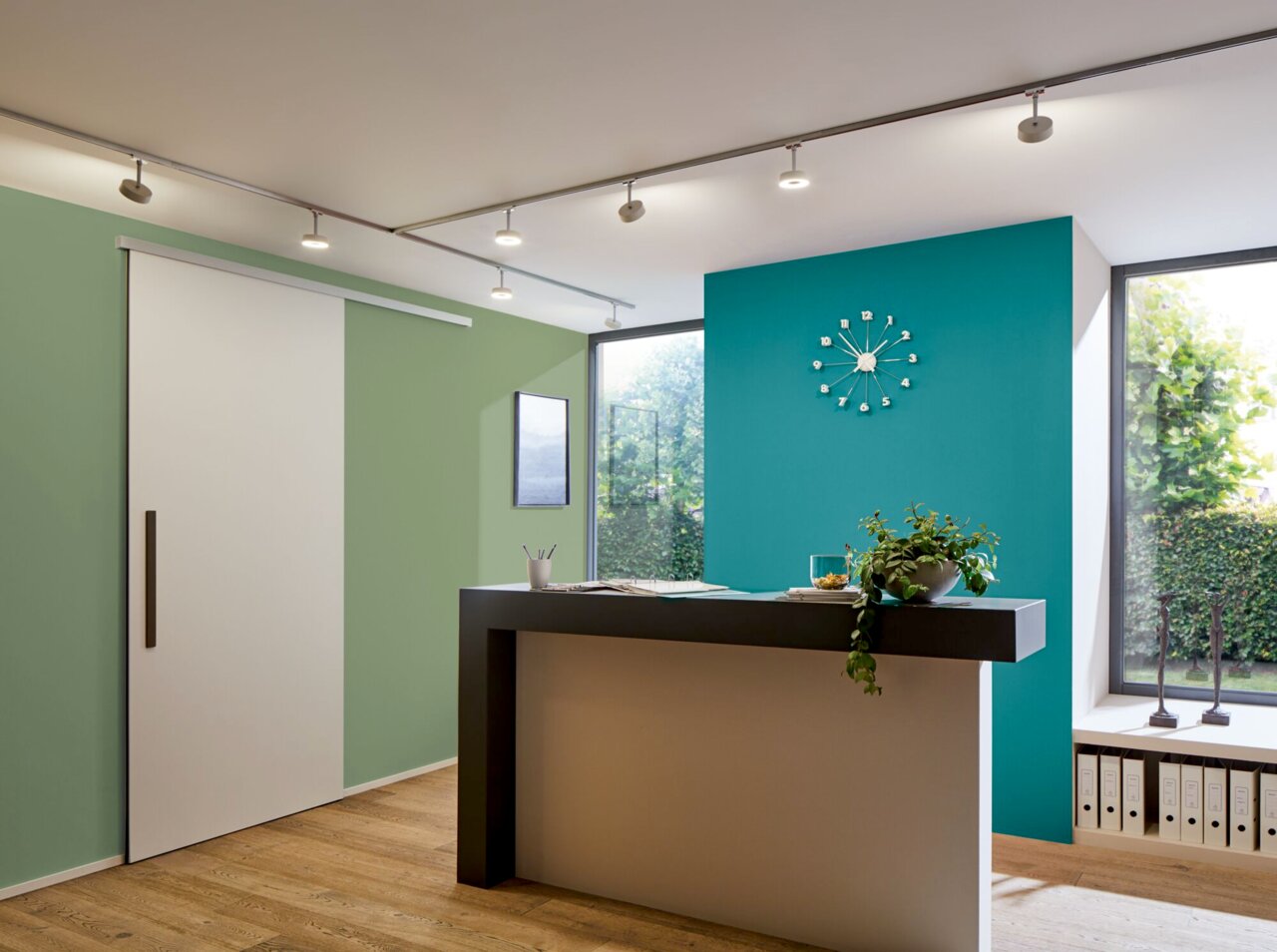Moderne Deckenbeleuchtung mit URail-System in einem stilvollen Raum mit Schiebetür und dekorativer Uhr an der Wand, seitliche Perspektive.