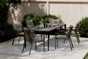 Gartensessel in einem modernen Garten-Set mit Tisch und mehreren Stühlen, seitliche Perspektive