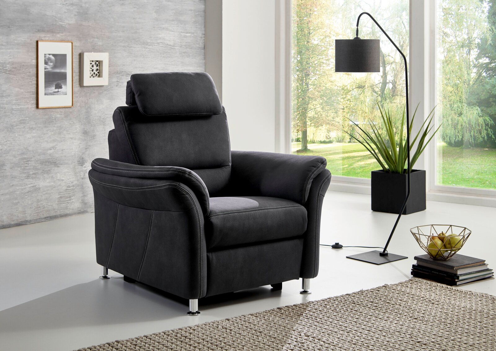 Moderner schwarzer Sessel mit verstellbarer Kopfstütze in einem hellen Wohnzimmer, seitliche Perspektive.