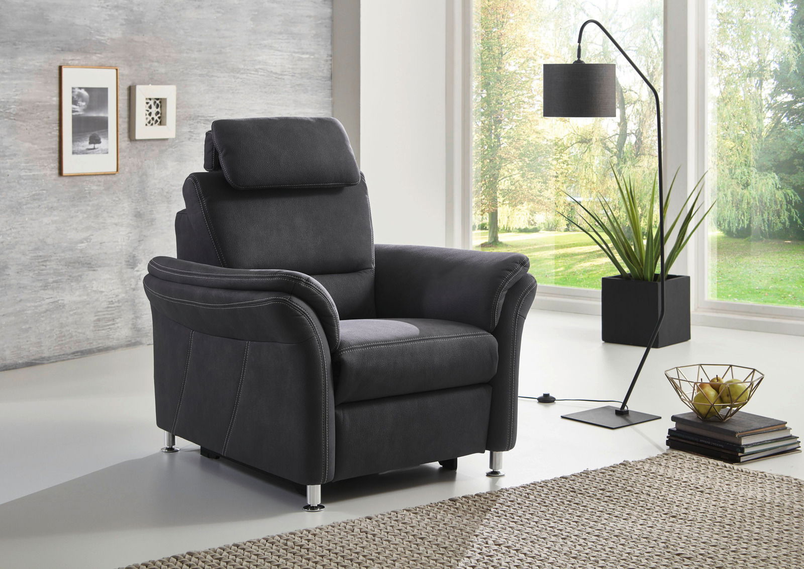 Moderner schwarzer Sessel mit verstellbarer Kopfstütze in einem hellen Wohnzimmer, seitliche Perspektive.