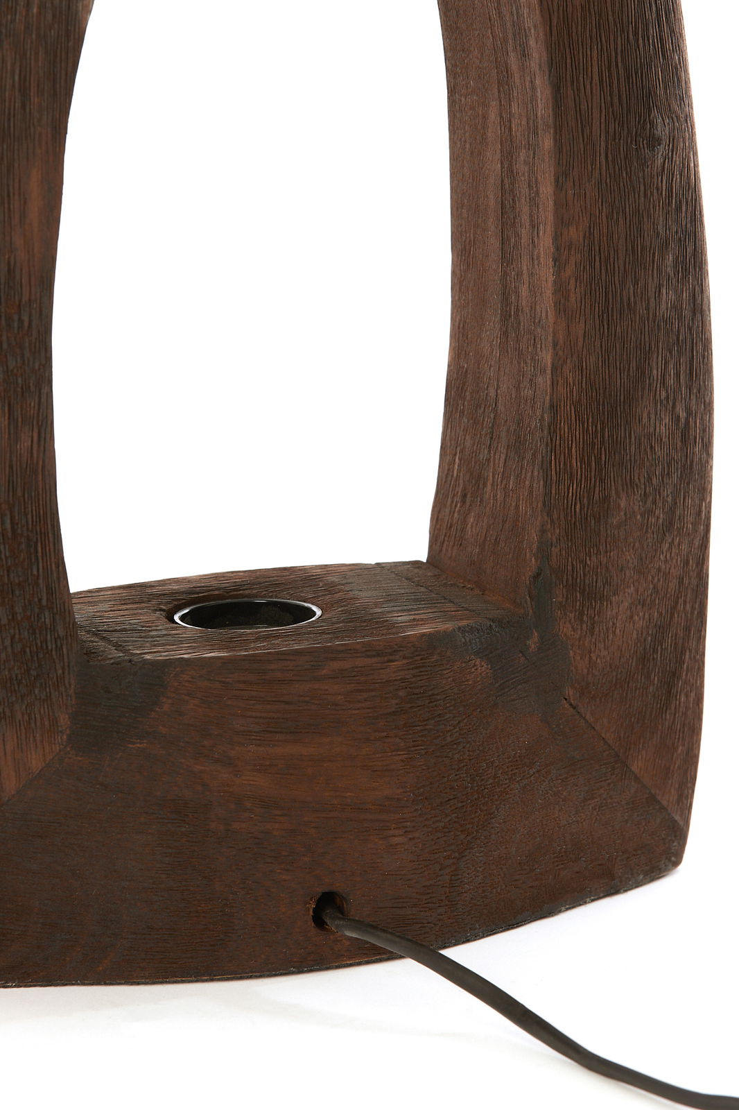 Nahaufnahme einer Tischleuchte aus dunklem Holz mit sichtbarer Kabeldurchführung, seitliche Perspektive.