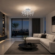 Elegante chromfarbene LED-Deckenleuchte mit filigranen, kristallbesetzten Zweigen, aus leichter Untersicht in einem modernen Wohnzimmer bei Abendlicht gezeigt
