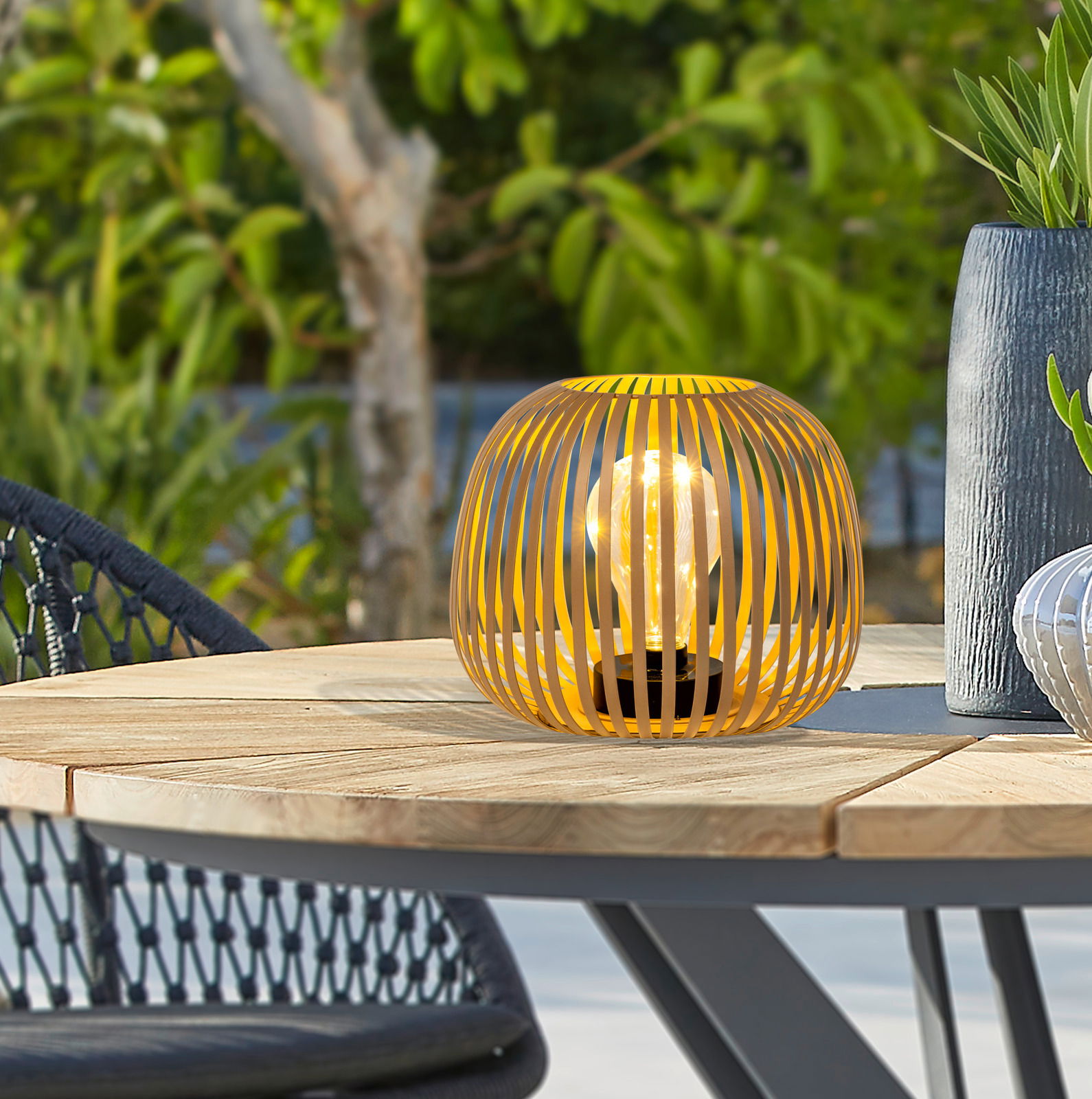 Ambia Garden Solarleuchte Gelbe Solarleuchte in moderner Gitteroptik auf einem Holztisch im Freien, seitliche Perspektive